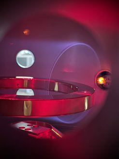 Floating particle trap: Here you can see the spiral paths in blue, on which electrons are forced by the ring's magnetic field. The luminous trail is created because the electrons excite the helium plasma in the vacuum chamber to glow.